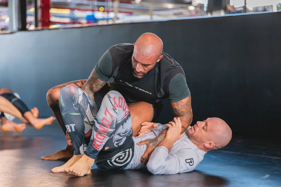 Two students training Brazilian Jiu-Jitsu on the mat.